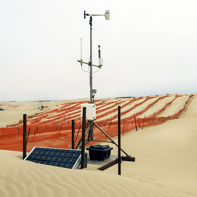 Image of sand dune, weather station, and orange wind fencing