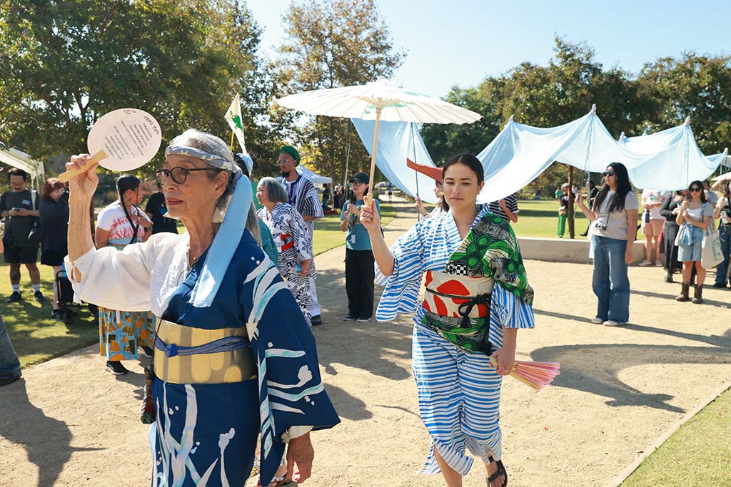 A crowd walks together through a park during a community procession.